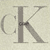 Static pixelated icon featuring a stylized CK monogram logo on a light beige background with subtle dithering.