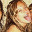 A pixelated image of a person with long brown hair, wearing a light-colored headband, and sticking out their tongue in a playful expression.