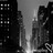 Black-and-white pixelated cityscape with tall buildings framing a central light source, rendered in low-resolution grayscale.