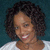 Pixelated portrait of a person with curly dark hair wearing a white top against a teal background.
