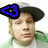 Pixelated image of a person wearing a dark cap with blue '<3' symbol on left side, green and white clothing visible.