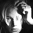 Black-and-white pixelated static icon showing a stylized human face in profile with visible hair and facial features against a dark background.
