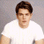 Pixelated image of a person with short brown hair wearing a white shirt against a gray background.