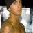 Pixelated close-up of a person's upper body and face with light skin tone, brown hair, and neutral expression against blurred background.