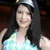 A pixelated static image shows a person with long dark hair wearing a light blue top against a dark background.