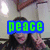 A person with long dark hair makes a peace sign in a room with light-colored walls and ceiling lights, with green text reading 'peace' overlaid on the top-left frame.
