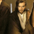 Static pixelated image of a person in formal attire with brown background and white vertical bar on left.