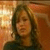 A four- shows a person with shoulder-length brown hair in dark clothing against an orange-brown background, displaying subtle facial expression changes