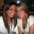 Two people with long brown hair wearing white tops, positioned closely together in a pixelated static image.