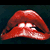 Red lips with white teeth and glossy texture on dark background, red dripping text reading ROCKY HORROR PICTURE SHOW on dark background.
