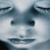Pixelated face with closed eyes, dark eyebrows, and a neutral expression on a light blue background.