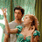 Two people in a forest pose with raised hands, the woman looking up at the man; cyan text "enchanted" appears below them.