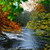 Pixelated landscape with green foliage, brown earth tones, and a blue water reflection under a light sky.