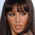 A static pixelated image of a person with long dark brown hair, bangs, and a neutral expression against a light background.