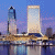 Pixelated cityscape with two towers on a bridge over water under blue sky, adjacent to green background with pixelated text.