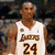 Pixelated image of a person wearing a white basketball jersey with brown text and number 24, standing against a dark background.