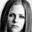 Black-and-white pixelated static image of a person's face with long hair, visible facial features including eyes and nose, and grayscale shading on a transparent background.