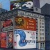 A static image of a building facade with multiple billboards, including a prominent blue and white wave-like graphic on a lower billboard.