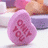 A pink oval-shaped icon with red text reading 'LOVE' in a stylized font, set against a blurred background of indistinct shapes and colors.