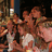 Pixelated image of a group of people in a crowded setting with red background text overlays.