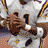 Pixelated football player in white uniform with yellow and purple accents, holding a ball, displayed alongside text and logo elements.