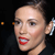 Pixelated close-up of a person's face with red lips, dark hair pulled back, and a small earring visible against a dark background.