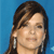 A pixelated close-up of a person with brown hair and a silver earring against a solid blue background.