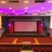 Static pixelated image of a theater interior with purple lighting, red pillars, and a central screen area on a wooden stage.