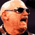 Pixelated static image of a bald character with light skin wearing dark sunglasses, orange-toned face and hair, against a black background.