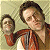 A pixelated image shows a person in a red jacket holding a smaller version of themselves against a light brown background.