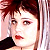 Static pixelated image of a person with short dark hair, red lips, and light skin holding a black microphone against a pinkish background.