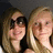 Two people with light brown hair pose closely together against a dark background, one wearing sunglasses and the other smiling.