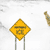 Yellow diamond-shaped road sign with 'ICE' text and a snowflake symbol, animated by a brown dog-like figure moving around it.