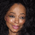Pixelated close-up of a person with light brown skin tone, dark eyebrows, and pink lips against a dark background.