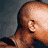 Animated contact sheet showing a bald man with dark skin in various poses including side profile, hand gestures, and kissing another person's cheek against gray background.