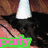 A black cat wearing a white cone-shaped hat sits on a wooden floor with pinkish-brown stripes, surrounded by colorful text overlays.