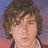 Pixelated close-up of a person with curly brown hair against a gradient background transitioning from blue to pink.