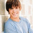 A pixelated image of a person in a light blue sweater against a blurred background, with pink text on a bright blue to the right