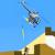 Pixelated static image showing a blurred figure in mid-air above a building with a blue sky background.