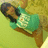 A person in a teal shirt with white text lies on a green surface, viewed from above.