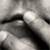 Black-and-white image of a person with closed eyes covering their mouth with one hand, transitioning from partial face view to full face view.