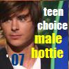 A pixelated image of a person with brown hair wearing a white shirt and dark jacket, with overlaid text reading 'teen choice male hottie 07' in various colors.