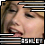Pixelated close-up of a person's face with closed eyes, framed by black and white striped borders; text 'ASHLEY' appears at the bottom right.