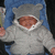 Pixelated static image of a figure in a gray hoodie with a brown circular face, blue background, and white trim around the hood opening.