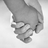 A black-and-white image of two hands clasped together on the left side, paired with purple pixelated text reading "These Hands Are Meant To Hold" on a black background to the right.