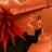 A pixelated static image shows a figure in dark clothing holding an object against a warm-toned background with red and orange hues.
