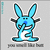 Pixelated blue bunny with large ears, black eyes and nose, white mouth showing teeth, dark gray arms crossed over chest, standing on flat base against light gray background.