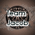 Two circular pixelated icons with brown textured backgrounds display text: 'Team Jacob' on the left and '4eva' on the right, each with a black heart symbol.