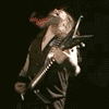 A musician with long hair plays a black electric guitar, head tilted back in motion