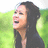 Pixelated image of a person with long dark hair in profile, mouth open in laughter against green background.